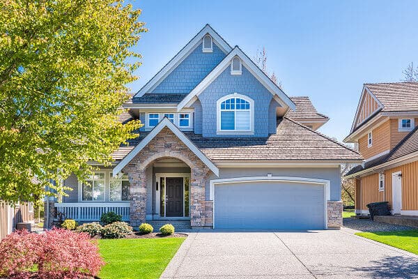Blue suburban home featuring a stone entryway and arched second-story window