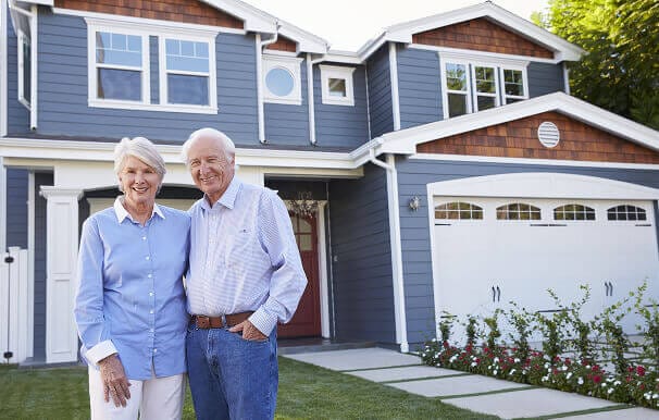 Happy couple standing in front of their home with new windows